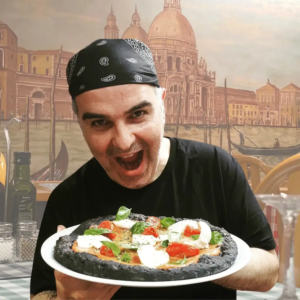 Luiggi al forn preparant una pizza amb massa negra de carbó vegetal